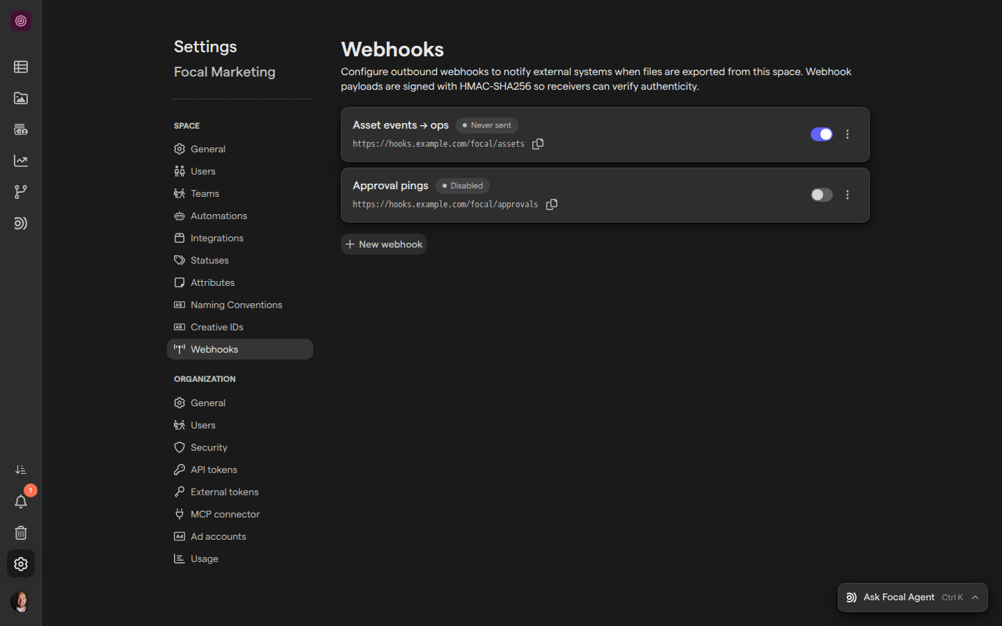 The Webhooks page of Space Settings for the Focal Marketing space, listing the active webhook Asset events → ops and the disabled webhook Approval pings, with a New webhook button below them.