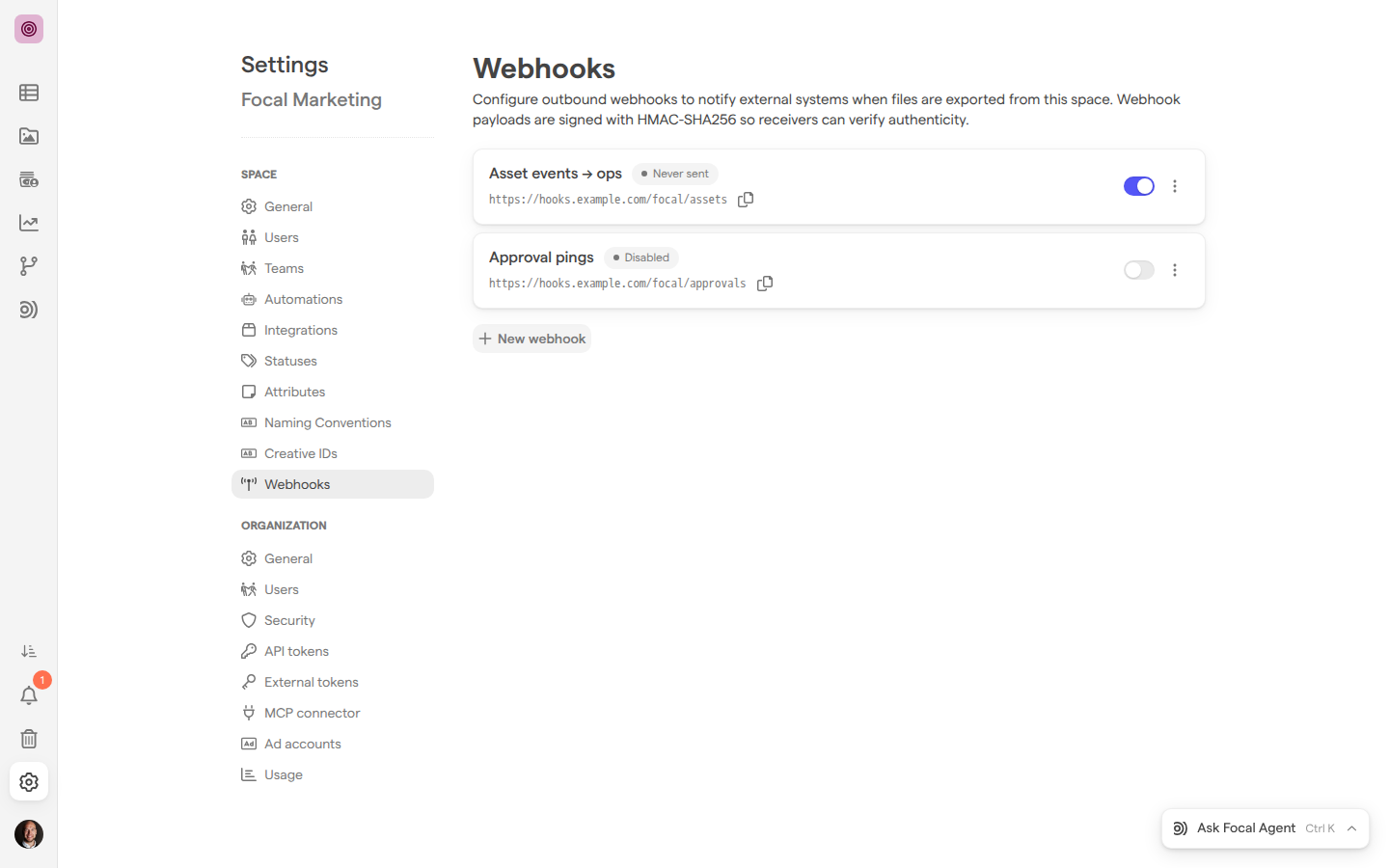 The Webhooks page of Space Settings for the Focal Marketing space, listing the active webhook Asset events → ops and the disabled webhook Approval pings, with a New webhook button below them.